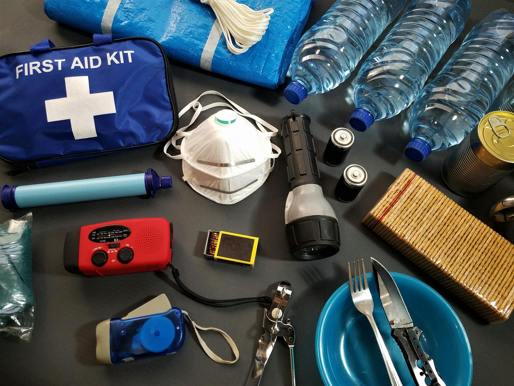 Half-empty emergency kit box with expired food and dead batteries on a shelf